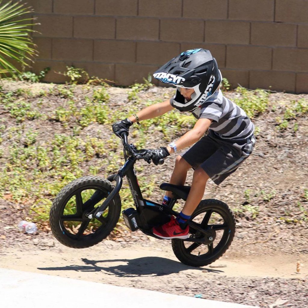 kid popping a wheelie on a stacyc electric bike